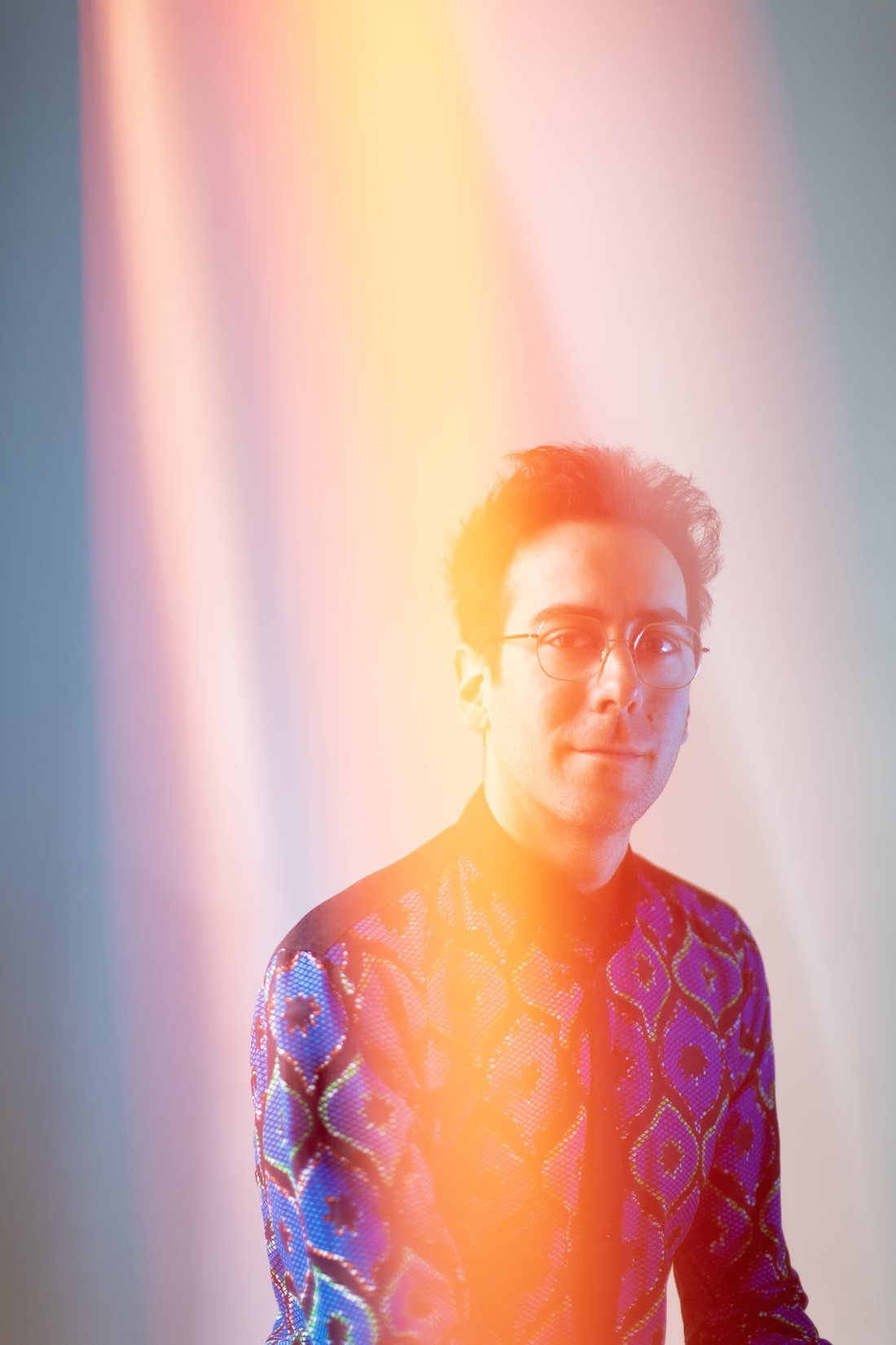 Portrait of Dexter Goldberg crossed by a halo of orange and pink light